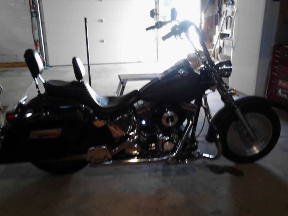 Black Harley-Davidson motorcycle with saddlebags and passenger backrests parked in a garage