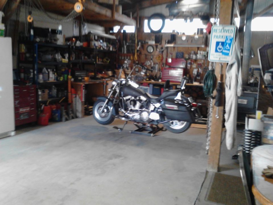 Motorcycle on a lift in a cluttered garage with tools and shelves