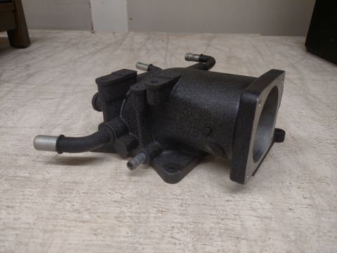 1995 Mercury Grand Marquis - A black metal throttle body is shown on a light-colored floor.