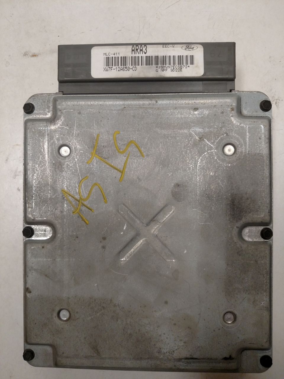 Silver Ford engine control unit with yellow markings and a barcode label