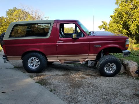 1995 Ford Bronco - This lifted 1995 Ford Bronco features a two-tone paint scheme with a tan removable top and side steps.