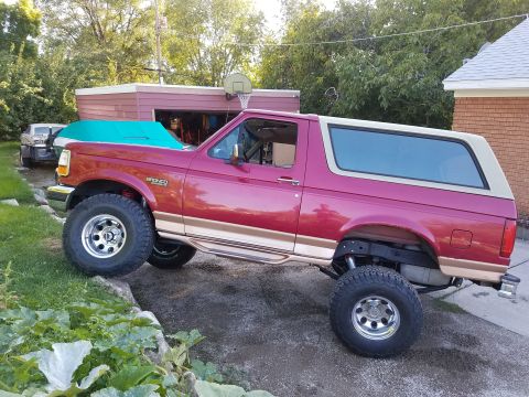 1995 Ford Bronco - Maroon 1995 Ford Bronco lifted with aftermarket wheels and tan top.