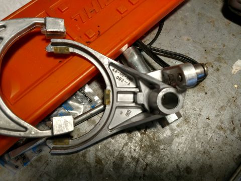 1992 Ford Bronco - A metal component, possibly from a transfer case, rests on a workbench next to an orange tool.