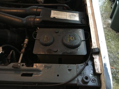 1988 Ford Bronco - Close-up view of the engine bay, showing the coolant and washer fluid reservoirs and associated hoses.