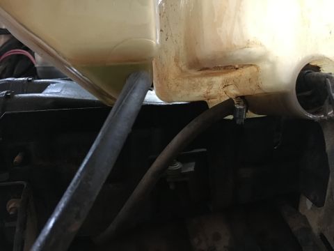 1988 Ford Bronco - Close-up of a vehicle's coolant reservoir and attached hose.