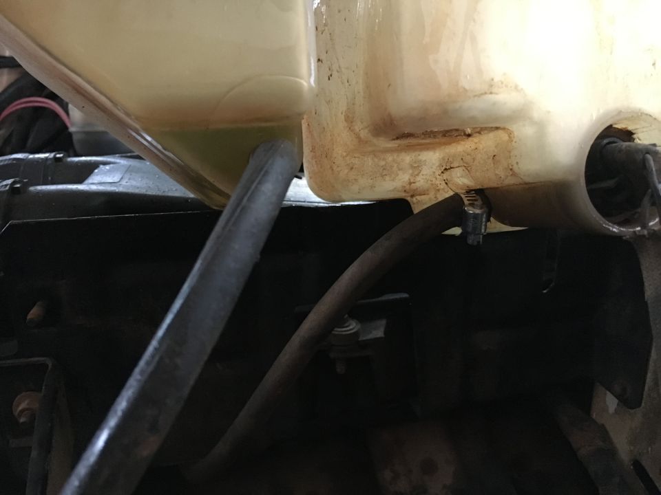 Coolant reservoir with yellow fluid and a hose attached
