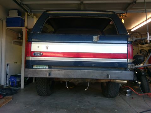 1988 Ford Bronco - Rear view of a 1988 Ford Bronco, a custom metal bumper and distinctive red, white, and silver tailgate stripe.