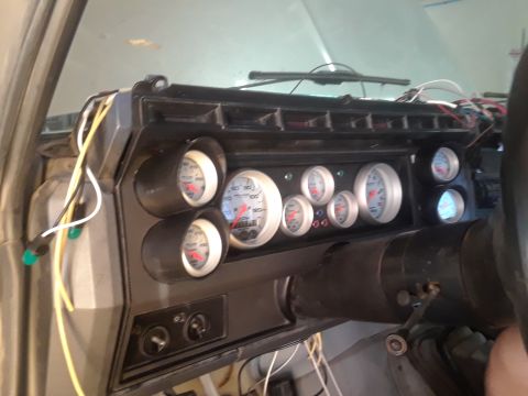 1985 Ford Bronco - A collection of aftermarket gauges are installed in the dashboard of a vehicle, with wiring exposed.
