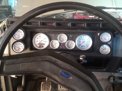 1985 Ford Bronco - The dashboard features a collection of aftermarket gauges, including a speedometer, tachometer, oil pressure, and voltage meters.