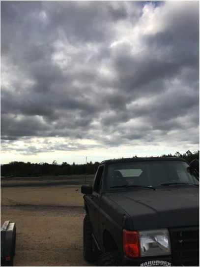 1989 Ford Bronco - 1989 Ford Bronco parked on dirt under a cloudy sky.