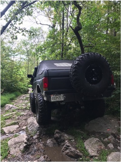 1989 Ford Bronco - This 1989 Ford Bronco navigates a rocky, muddy trail in a wooded area.