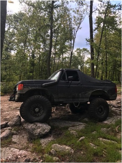 1989 Ford Bronco - This lifted 1989 Ford Bronco navigates rocky terrain, equipped with a snorkel for off-road adventures.