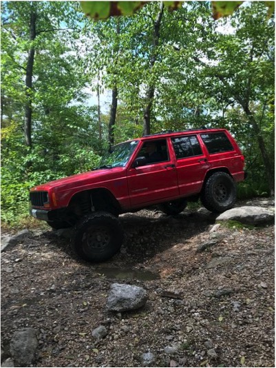 1989 Ford Bronco - This red Jeep Cherokee XJ navigates a challenging rocky trail, its off-road capabilities.