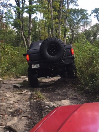1989 Ford Bronco - Off-roading in a 1989 Ford Bronco on a wooded trail with another vehicle nearby.