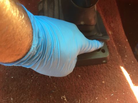 1986 Ford Bronco - Hand in a blue glove presses a pedal on the floor of a vehicle.