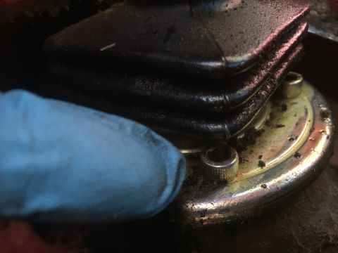 1986 Ford Bronco - A close-up shows a dirty gear shifter boot and its base, with a blue glove in the foreground.