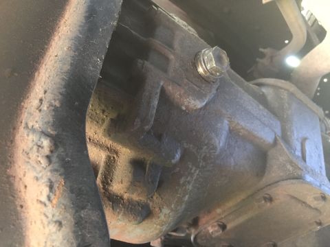 1986 Ford Bronco - Close-up of a transmission housing, showing mechanical components and a bolt.