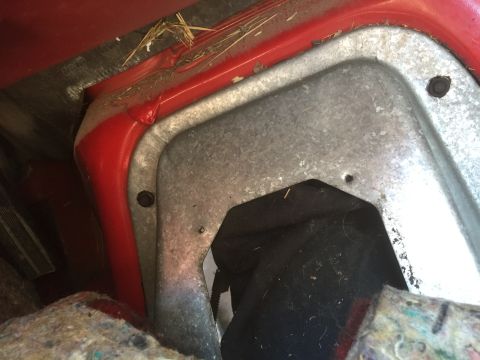 1986 Ford Bronco - Close-up view of a vehicle's interior, showing a red panel and a metal cover with fasteners.