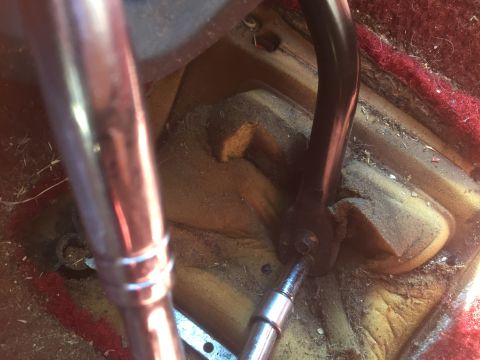 1986 Ford Bronco - Close-up of the floor area inside a vehicle, showing mechanical linkage and worn carpeting.