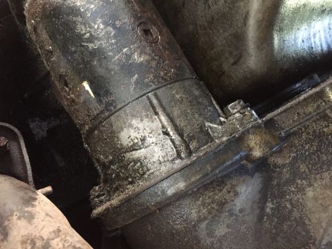 1986 Ford Bronco - Greasy starter motor assembly on a vehicle transmission.