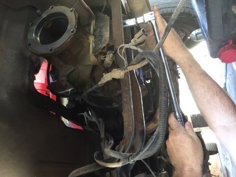 1986 Ford Bronco - Mechanic works on the transmission of a vehicle, focusing on adapter plate installation.