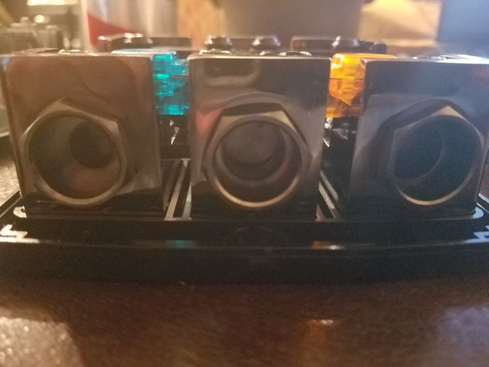 Close-up of a car stereo power distribution block with three ports, two with blue and orange fuses