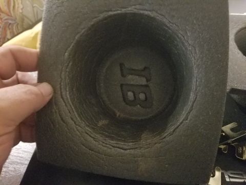 1994 Ford Bronco - A close-up of a cracked speaker housing with an embossed 'JB' logo, held by a person's hand.