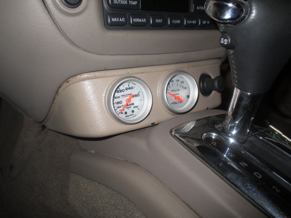 Car interior with transmission shifter and two gauges, one for transmission temp and one for volts