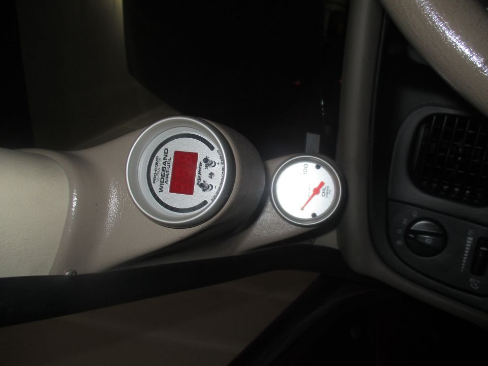 Interior view of a wideband air/fuel gauge and an oil pressure gauge mounted on a tan dashboard