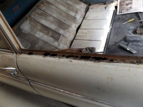 1962 MG B - Interior view of a car showing significant rust damage along the door sill and floor.