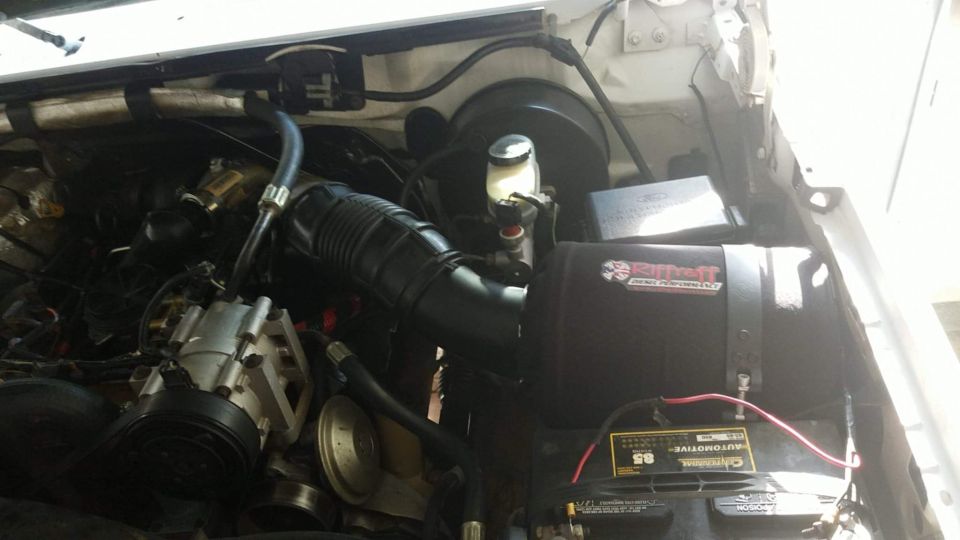 Engine bay with black Riffraff Diesel Performance intake, corrugated intake tube, and Centennial battery