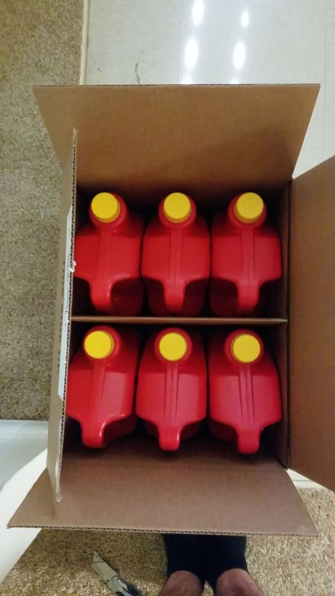 1995 Ford F-250 - Six red oil jugs are packed in a cardboard box, with a Supermotors.net logo at the bottom.