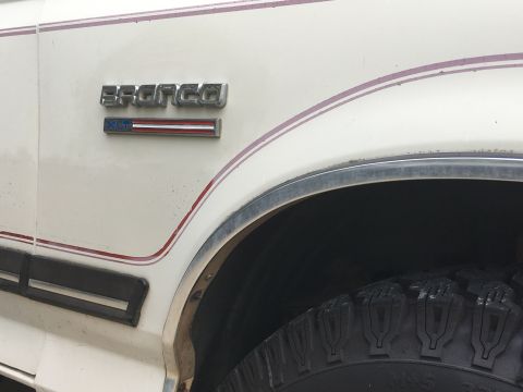 1988 Ford Bronco - Close-up of the fender emblem on a white 1988 Ford Bronco.