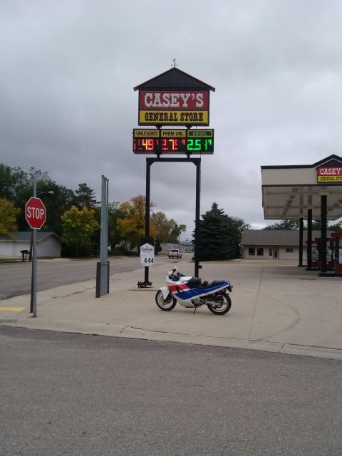 1989 Honda CBR600F - A 1989 Honda CBR600F is parked on the sidewalk in front of a Casey's General Store, with gas prices displayed on a tall sign.