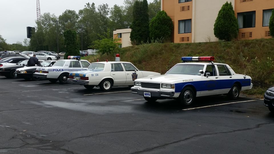Several police cars parked in a lot, including a white and blue car with 'POLICE' on the door