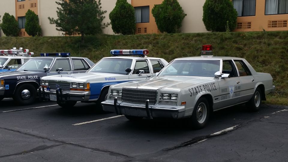 Several police cars parked in a lot, including a silver car with "STATE POLICE" on the door