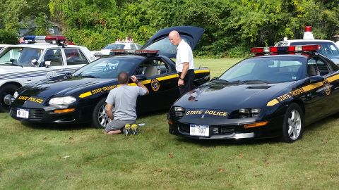 1991 Ford LTD Crown Victoria - State Police vehicles parked on grass with personnel attending to them.