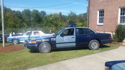 1991 Ford LTD Crown Victoria - A Massachusetts State Police car is parked next to a brick building, with another police vehicle visible in the background.