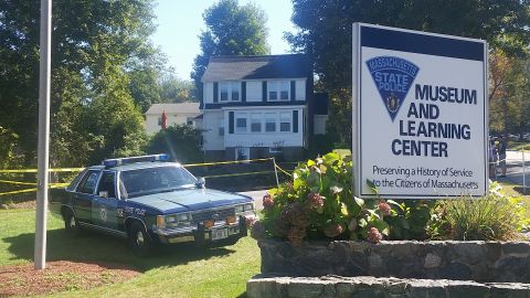 1991 Ford LTD Crown Victoria - A Massachusetts State Police car is parked outside the museum and learning center, with police tape cordoning off the area.