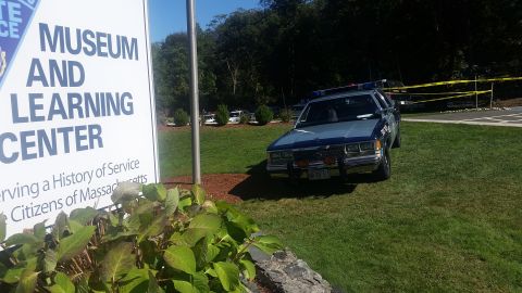 1991 Ford LTD Crown Victoria - A 1991 Ford Crown Victoria police car is parked on the lawn near a sign for the Massachusetts State Police Museum and Learning Center.
