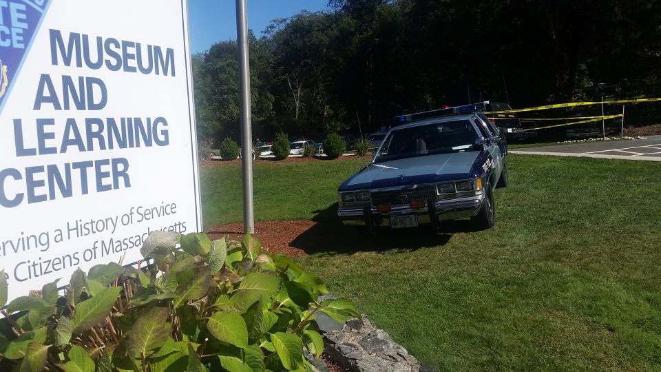 1991 Ford Crown Victoria police car parked on grass, front 3/4 view, blue and grey