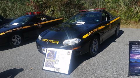 1991 Ford LTD Crown Victoria - Two black police cars with "STATE TROOPER" and "STATE POLICE" markings are displayed outdoors.