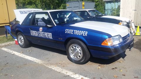 1991 Ford LTD Crown Victoria - A Georgia State Patrol Ford Mustang GT police car is parked next to another similar vehicle.
