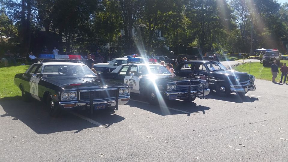 Several old police cars parked in a lot, one with a light bar