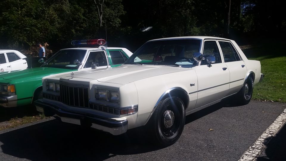 White sedan with chrome trim and black wheels, parked on asphalt