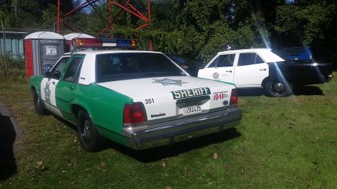 1991 Ford LTD Crown Victoria - A 1991 Ford Crown Victoria Sheriff's car is parked next to another police vehicle, with portable toilets in the background.
