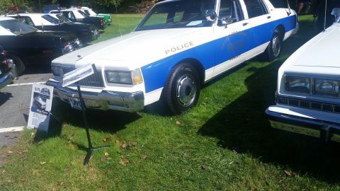 1991 Ford LTD Crown Victoria - A 1991 Ford Crown Victoria police car is displayed on a grassy field next to other vehicles.