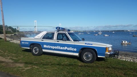 1991 Ford LTD Crown Victoria - A 1991 Ford Crown Victoria police car is parked by the water with a bridge in the background.