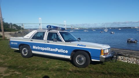 1991 Ford LTD Crown Victoria - A 1991 Ford Crown Victoria police car is parked by the water with a bridge in the distance.