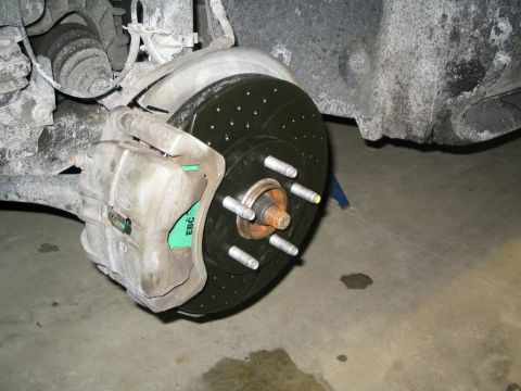 1996 Mercury Sable - A close-up view of a car's brake system, highlighting a new drilled and slotted rotor and EBC brake pads.